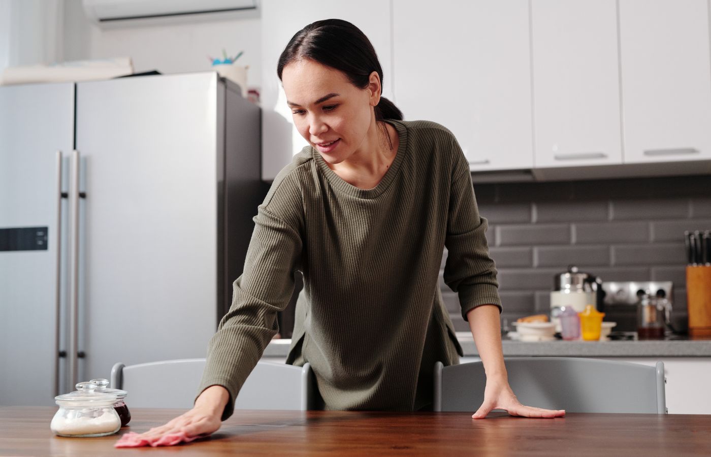 A support worker wiping down a table while cleaning a client's home