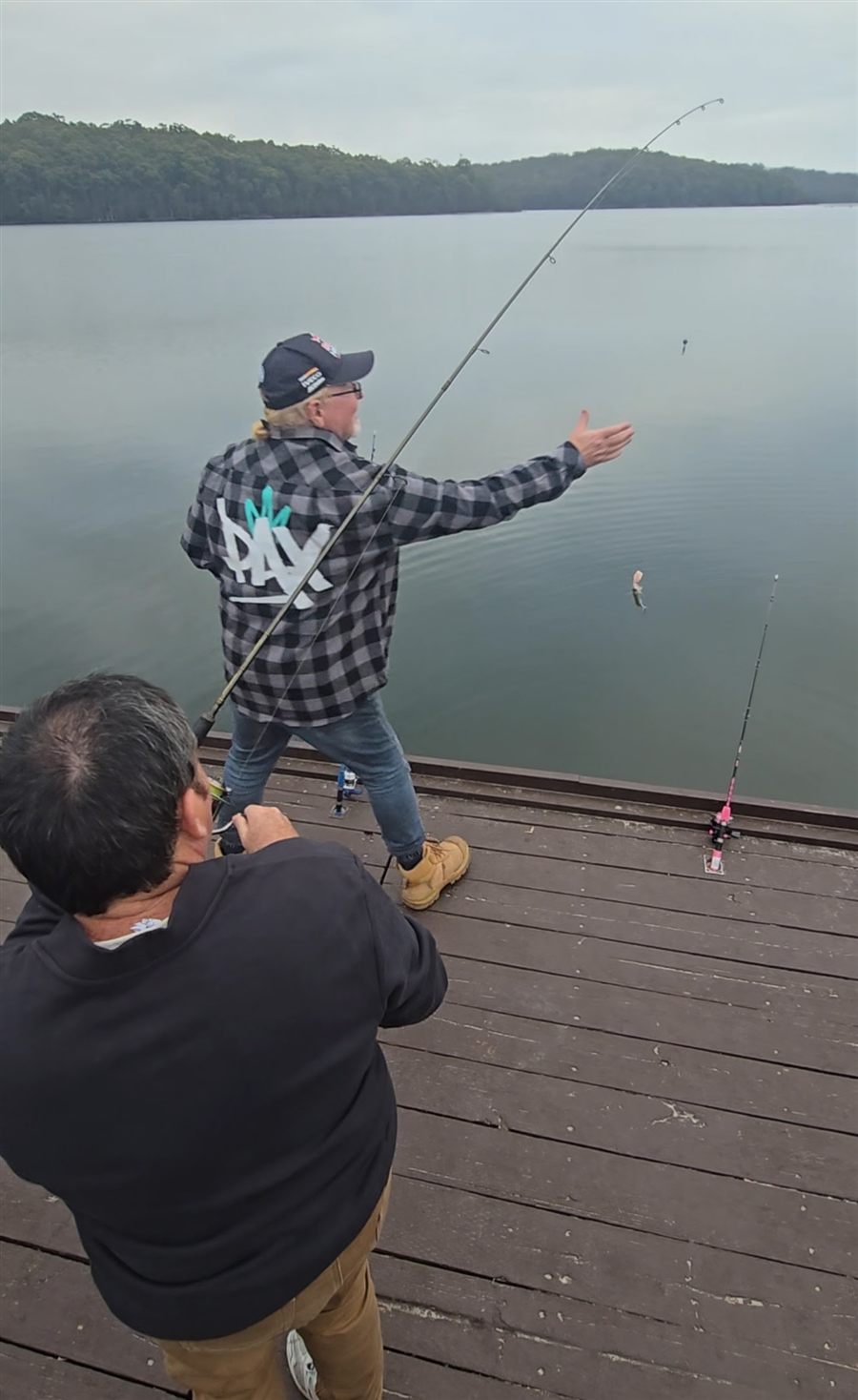 Participants fishing together from a jetty on a quiet lake